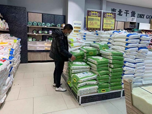 顾客在苏北粮油投放超市的大米货架挑选大米